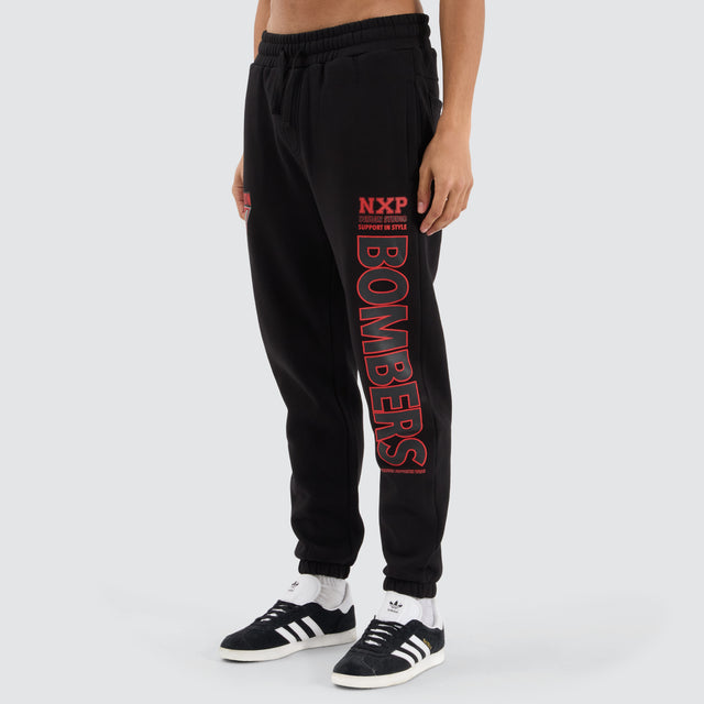 Model Wears Essendon Bombers AFL Trackpant Jet Black Trackpants in Black - Image 1