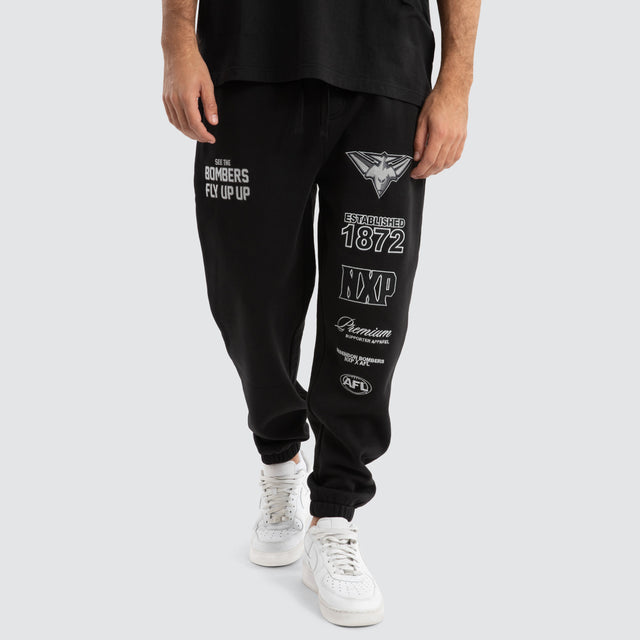 Model Wears Essendon Bombers AFL Mono Trackpants Jet Black Trackpants in Black - Image 1