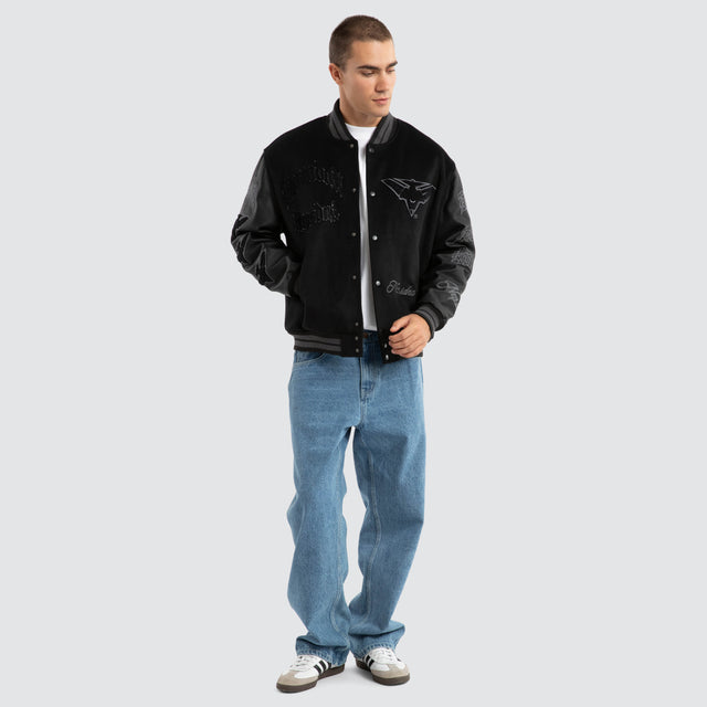 Model Wears Essendon Bombers AFL Ace Varsity Jacket Jet Black Jackets in Black - Image 2