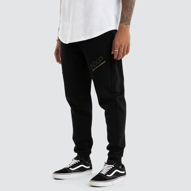 Model Wears Turret Slim Trackpant Jet Black Trackpants in Black - Image 1