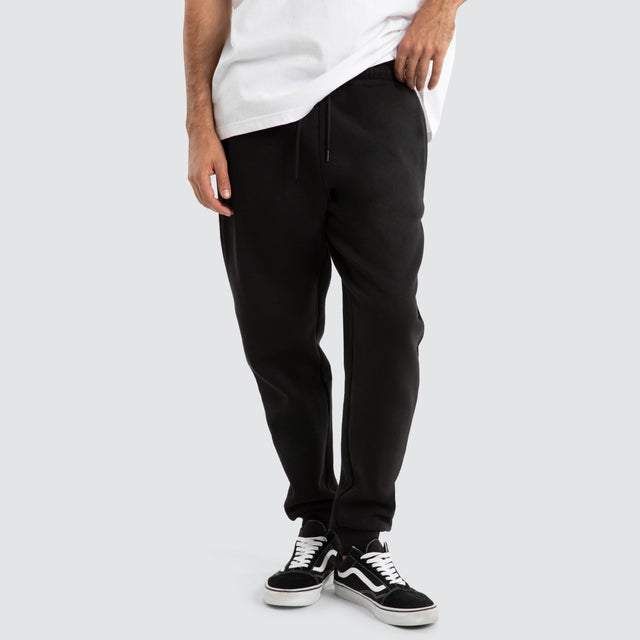 Model Wears Supply Skinny Trackpant Jet Black Trackpants in Black - Image 1