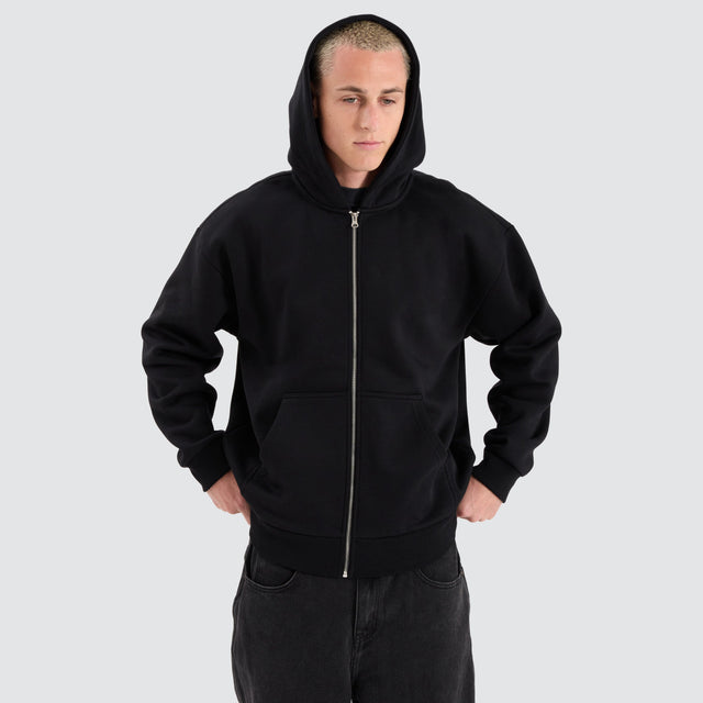 Model Wears Rosthern Relaxed Zip Through Hoodie Jet Black Jumpers in Black - Image 7