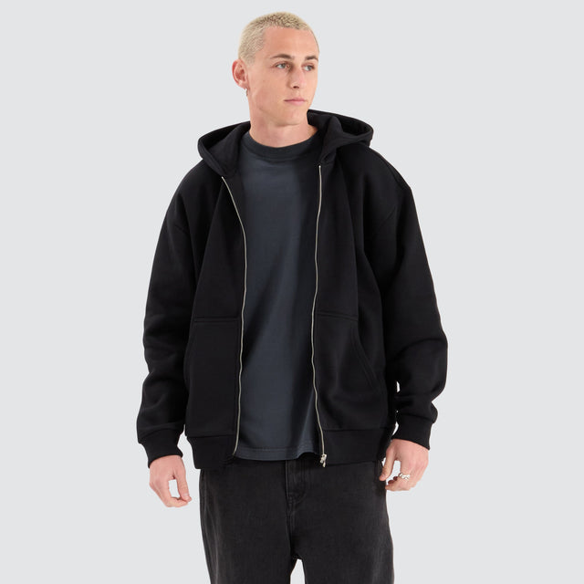 Model Wears Rosthern Relaxed Zip Through Hoodie Jet Black Jumpers in Black - Image 1