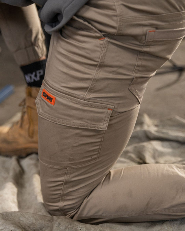 Welder bending at work in the Cross over workwear jogger pant in sand