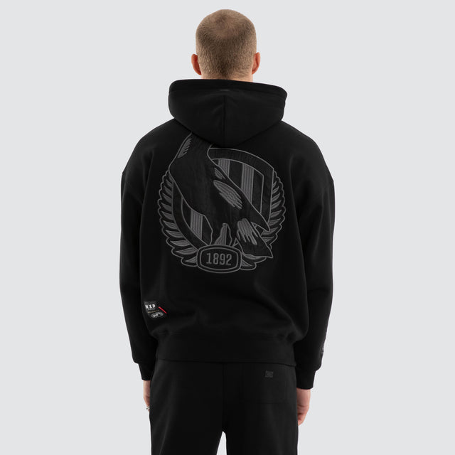 Model wears Collingwood Magpies AFL Persistent Hoodie Jet Black Hoodies in Black - Image 3