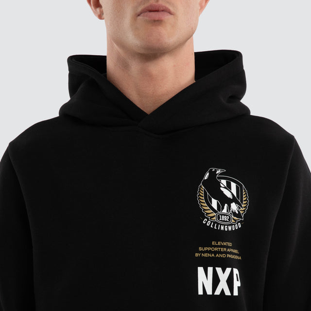 Model wears Collingwood Magpies AFL Trophy Curved Hem Hoodie Jet Black Hoodies in Black - Image 3