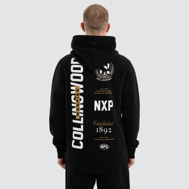 Model wears Collingwood Magpies AFL Trophy Curved Hem Hoodie Jet Black Hoodies in Black - Image 1