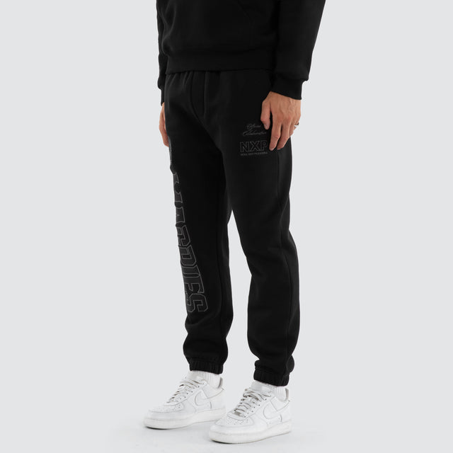 Model wears Collingwood Magpies AFL Perform Trackpant Jet Black Trackpants in Black - Image 1