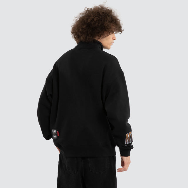 Model wears Ben Davis Hawthorn Hawks AFL 1/4 Zip Thru Jet Black Pullover in Black - Image 5
